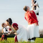 Joyful family in traditional attire playing in a sunny field, embracing cultural heritage.
