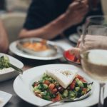 A beautifully arranged dinner setting featuring fresh salad and white wine, perfect for a fine dining experience.
